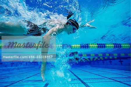 Female swimmer racing underwater in pool