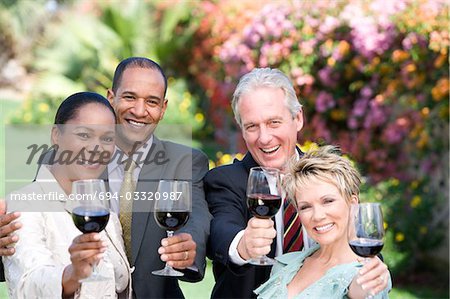 Two couples holding wine outdoors, portrait