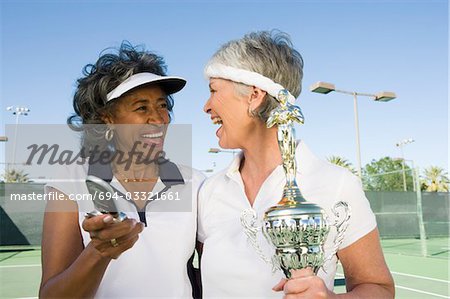 Two female tennis players with award cup