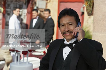Man in tuxedo at Quinceanera, using mobile phone