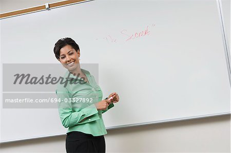 Business woman standing in front of whiteboard, laughing