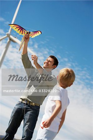 Father and son (7-9) playing with kite at wind farm