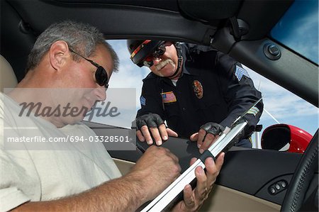 Police officer watching driver signing papers, view from car