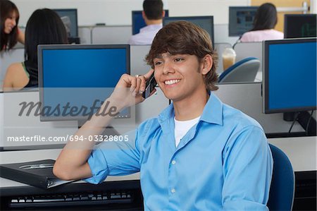 Male student using mobile phone in computer classroom