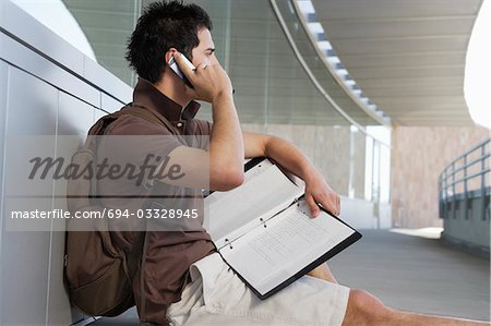 Male student using mobile phone outside school