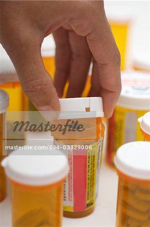 https://image1.masterfile.com/getImage/694-03329006em-mans-hand-opening-pill-bottle-closeup-stock-photo.jpg