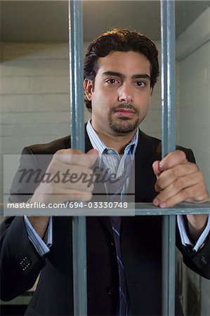 Man standing behind cell bars