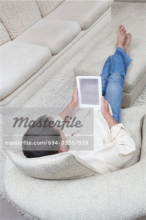 Man sits with feet up reading a digital book