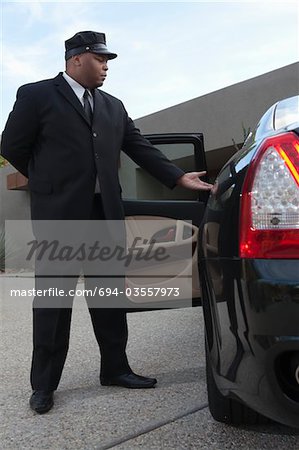 Chauffeur extends hand to client in  luxury vehicle