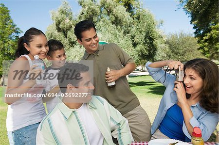 Woman using digital camera, photographing son (13-15) with father, brother, and sister.