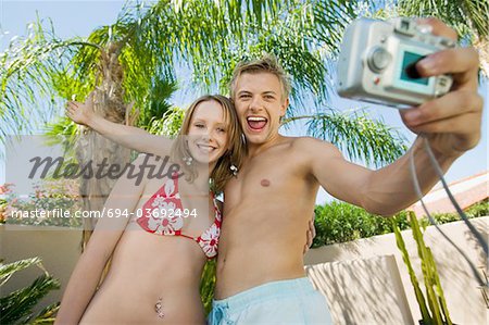Young couple taking photo of themselves, low angle view