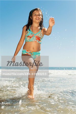 Girl in swimwear running in sea