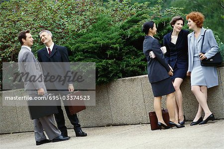 Business executives standing outdoors in groups, chatting
