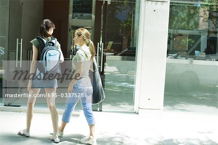 Two young women walking toward doorway together