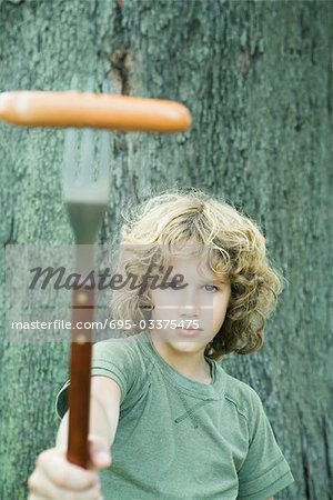 Boy holding up hot dog on fork