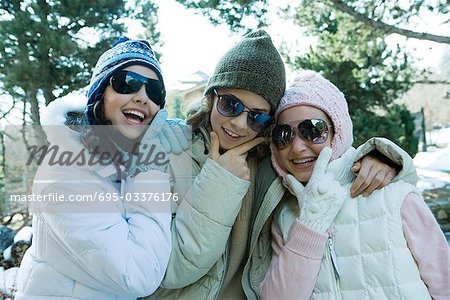 Three teen girls wearing winter clothes and sunglasses, holding