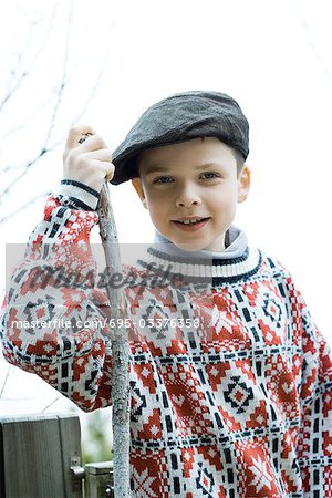 Boy wearing traditional sweater and cap, holding hiking stick