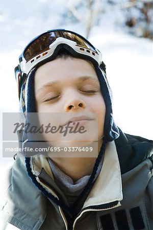 Boy in ski gear smiling with eyes closed, high angle view