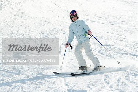 Teenage girl skiing on ski slope, full length