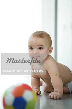 Baby on floor, ball in blurred foreground
