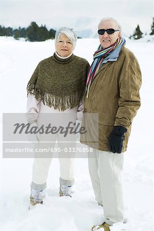 Senior couple standing side by side outdoors, looking at camera, portrait