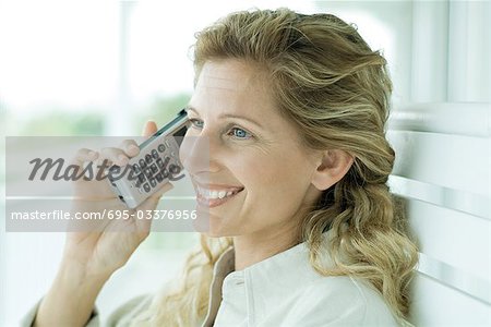 Woman using cell phone, smiling, portrait
