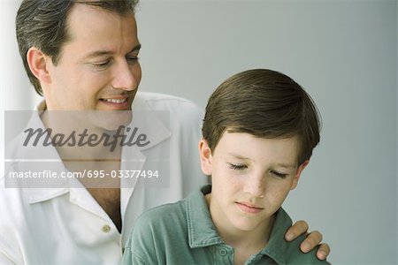 Father and son looking down and smiling together, close-up