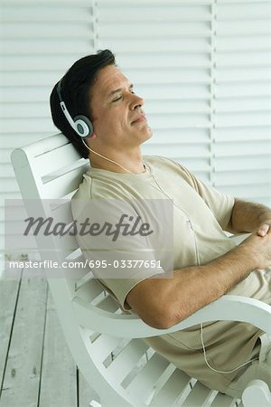 Man sitting in rocking chair, listening to headphones