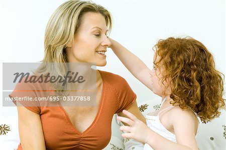 Mother and daughter looking at each other, smiling, girl's arm raised