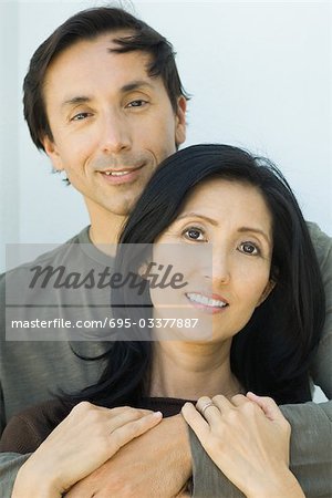 Couple embracing, both smiling at camera, portrait