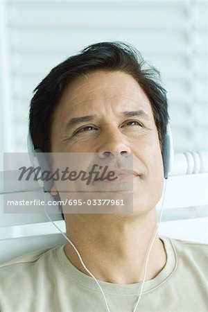 Man listening to headphones, looking up, close-up