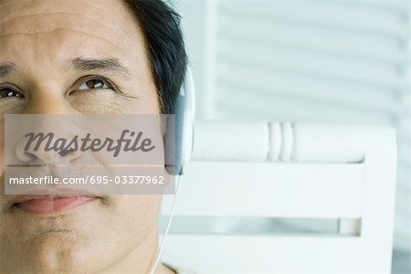 Man listening to headphones, looking up, cropped view