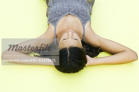 Teenage girl lying on back with hands under head, eyes closed, high angle view