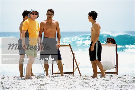 Family at the beach, chatting, two men looking at camera