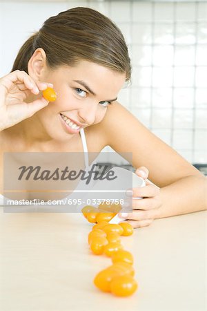 Young woman spilling dish of cherry tomatoes, smiling at camera