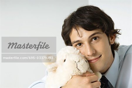 Young man holding stuffed toy against cheek, smiling at camera - Stock Photo - Masterfile - Premium Royalty-Free, Code: 695-03379383 Young man holding stuffed toy against cheek, smiling at camera - Stock Photo - Masterfile - Premium Royalty-Free, Code: 695-03379383