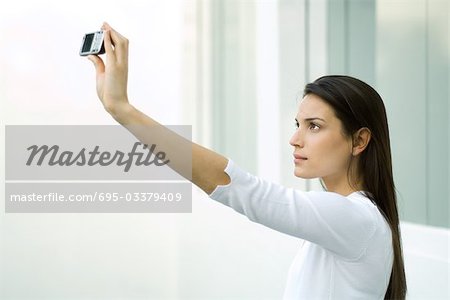 Woman photographing herself with photophone, arm raised