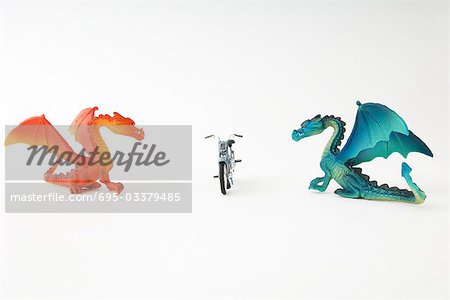 Toy dragons facing each other with toy motorcycle between them