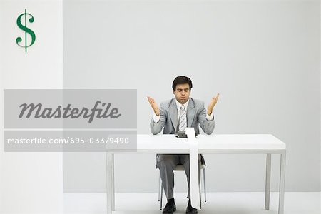 Man sitting at desk with adding machine, puffed cheeks, hands raised
