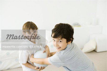 Two boys playing with ball, smiling at camera