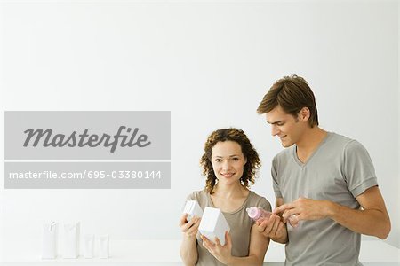 New parents looking at milk cartons, man holding baby bottle, woman smiling at camera