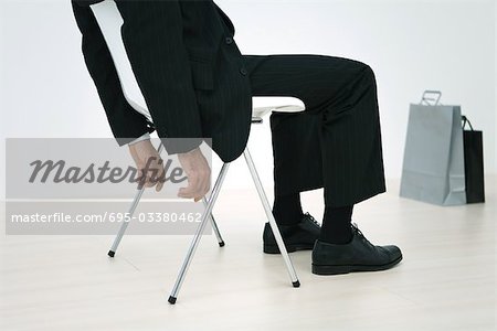Businessman sitting, with shopping bags on floor