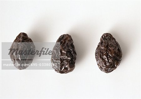 Three prunes against white background, close-up