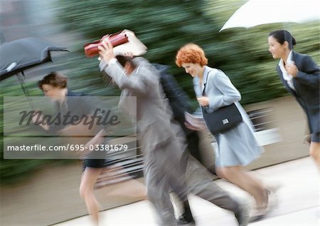 Businesspeople running in rain, blurred