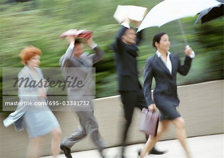 Group of business people running in rain, blurred