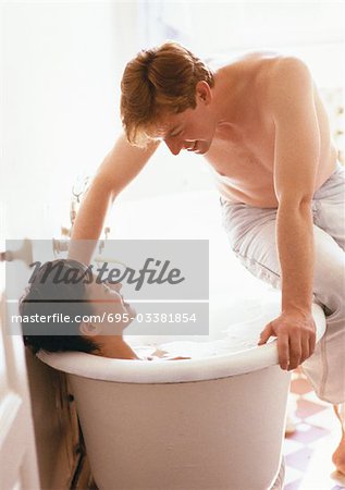 https://image1.masterfile.com/getImage/695-03381854em-woman-taking-bath-man-sitting-on-side-of.jpg