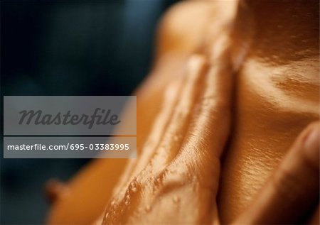 Woman's wet hand on bare chest, close-up - Stock Photo