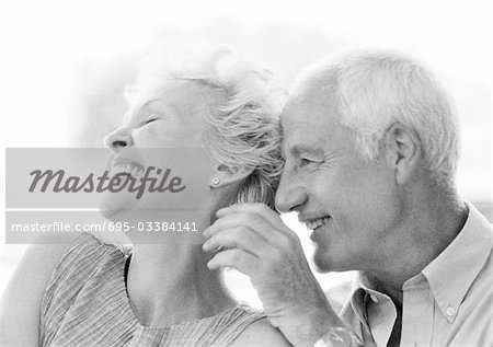 Mature man and woman smiling, close-up, B&W
