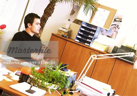 Man sitting at desk in office, side view