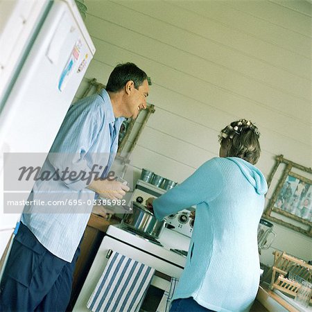 Mature couple in kitchen, woman cooking